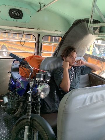 On a chicken bus with a motorbike loaded next to a seat — Central America.