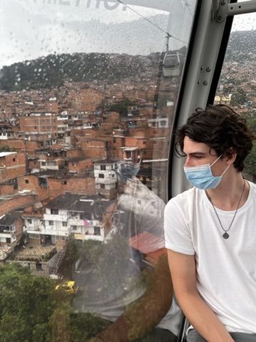 Tom in a cable car over Medellín during COVID — mask, comuna below.