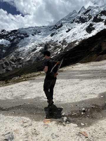 Tom hiking toward a glacier with an ice axe, alpine landscape.