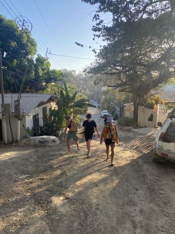 Friends walking down a dusty street into the sun, tropical.